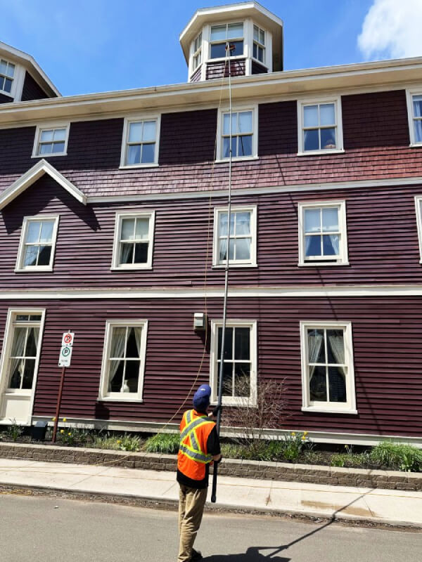 A Best View window cleaner uses a water-fed pole system to wash the high exterior windows of a three-story building in Charlottetown.