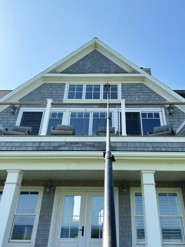 High-reach residential window cleaning in Charlottetown using a water-fed pole on a three-story home.